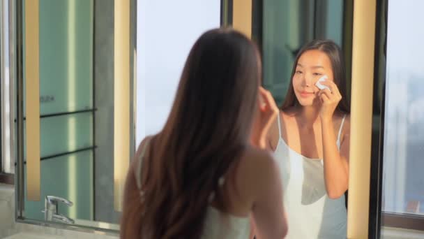 Güzel Asyalı bir kadının portresi banyo içi aynası ile kozmetik kullanıyor. - Video, Çekim