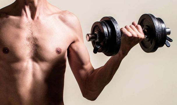 Man holding dumbbell in hand. Skinny guy hold dumbbells up in hands. A thin man in sports with dumbbells. Weak man lift a weight, dumbbells, biceps, muscle, fitness. Nerd maleraising a dumbbell - Photo, Image