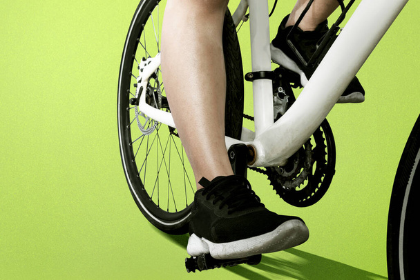 Side view of a woman riding a bicycle with colored background - Foto, imagen