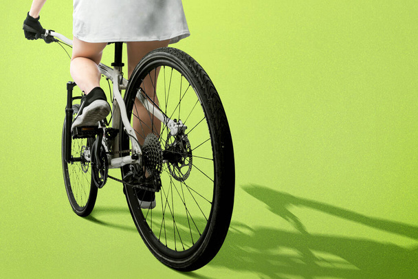 Rear view of a woman riding a bicycle with colored background - Foto, imagen