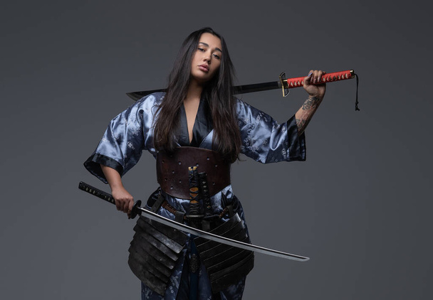 Mujer peligrosa samurai posando con espadas de samurai - Foto, imagen