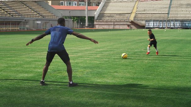 Nero padre cercando di prendere palla da figlio durante l'allenamento di calcio - Foto, immagini