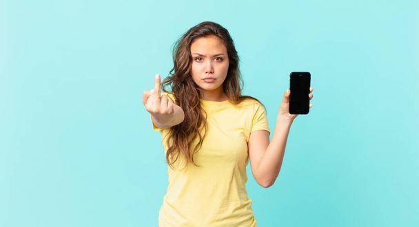 young pretty woman feeling angry, annoyed, rebellious and aggressive and holding a smart phone - Фото, зображення