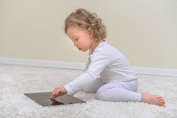 Little girl draws or plays on the tablet computer. - Fotó, kép