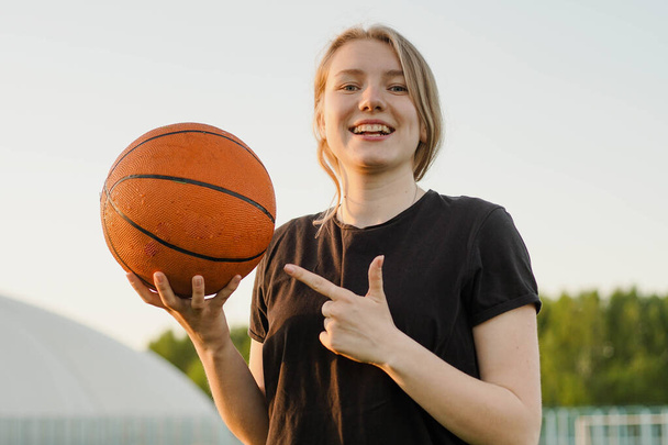 Портрет усміхненої дівчини-підлітка баскетболіста, який вказує пальцем на м'яч
 - Фото, зображення