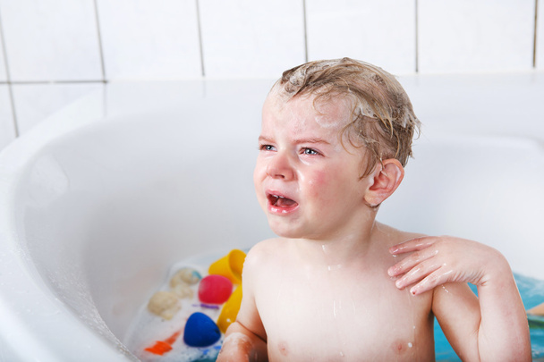 Cute little toddler boy of two years having fun by taking bath i - Photo, Image