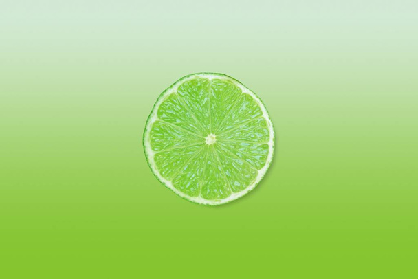 green lime slice over matching colour gradient background with copy space - Photo, Image