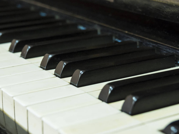 Černobílé opotřebované klávesy starého klavíru, fotografie pod úhlem. - Fotografie, Obrázek