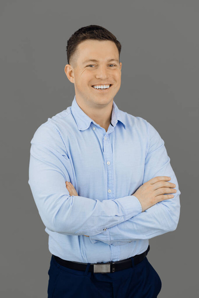 Handsome, smiling and self-sufficient man on gray background looks confidently at the camera. Online education concept. - Photo, Image