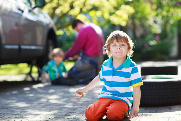 padre y dos niños pequeños reparando coche y cambiando de rueda toge
 - Foto, imagen