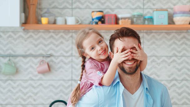 Una bambina in età prescolare copre i suoi occhi papà con le mani - Foto, immagini