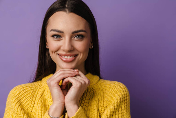 Happy beautiful brunette girl smiling and looking at camera isolated over purple background - Фото, изображение