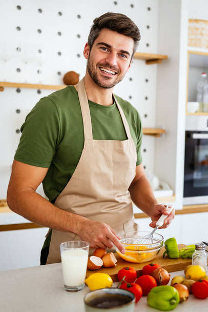 Cheerful young man preparing healthy food in the kitchen at home - Photo, image