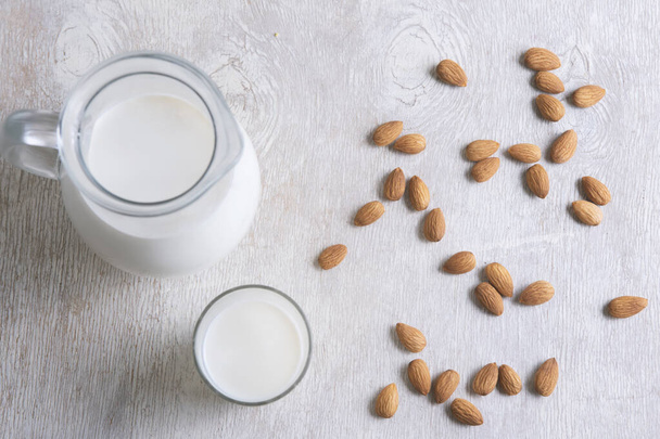 almond and milk in a jug and a glass on a white wooden background.top wiev - Foto, immagini