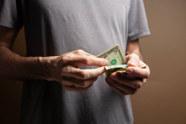 Hombre contando dinero sobre fondo marrón - Foto, imagen