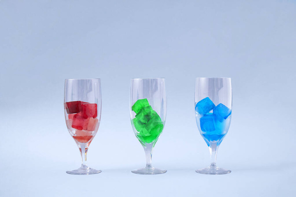 Tvůrčí koncept tří sklenic na víno s rgb ledem. Ledově červené, zelené a modré koktejly na šedém pozadí. - Fotografie, Obrázek
