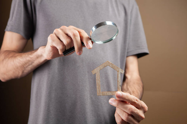 magnifying glass looks at the house. real estate search on brown background - Photo, Image