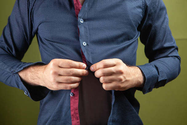 a man straightens the buttons of his shirt on a green background - Fotoğraf, Görsel