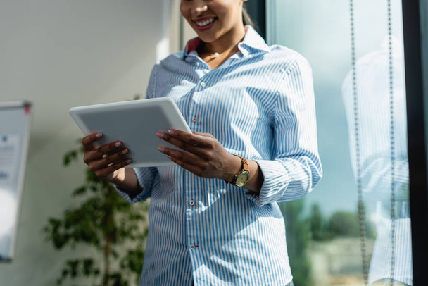 cropped view of smiling african american businesswoman with digital tablet in office - Foto, immagini