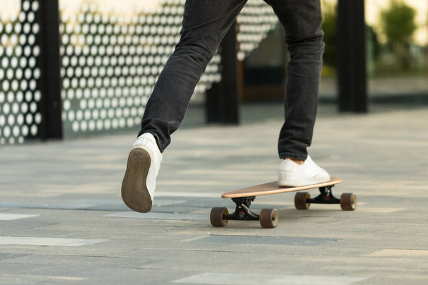 Man skateboarder rijden longboard in de stad, buiten, bijgesneden beeld. Vrije tijd, gezonde levensstijl, extreem sportconcept - Foto, afbeelding