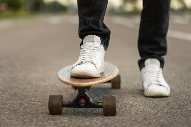 Man skateboarder standing on longboard, outdoors. Leisure, healthy lifestyle, extreme sports  - Photo, Image