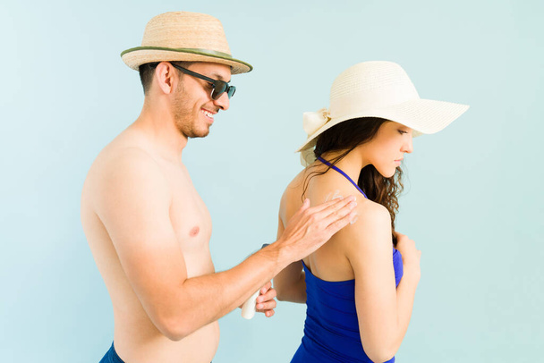 Bello fidanzato felice di applicare crema solare lozione nella parte posteriore della sua bella ragazza caucasica mentre in vacanza sulla spiaggia - Foto, immagini