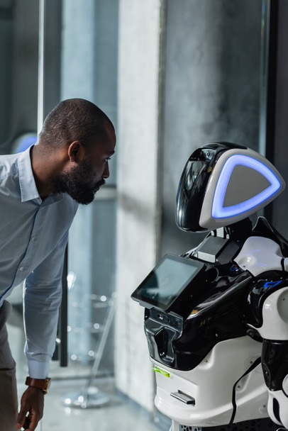 african american businessman looking at robot in office - Foto, immagini