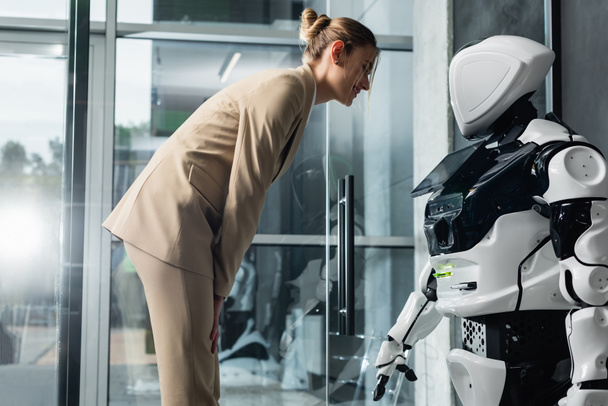 smiling businesswoman looking at robot in office - Foto, Imagem