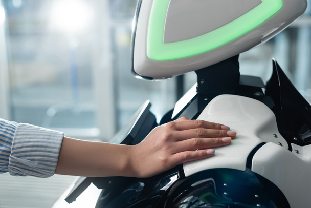 Ausgeschnittene Ansicht einer Frau, die Roboter im Büro mit der Hand berührt - Foto, Bild