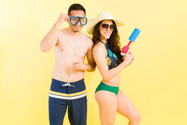 Google şnorkelli ve su tabancalı neşeli bir çiftin portresi. Yaz tatilleri boyunca kumsalda ve havuzda harika vakit geçirmeye hazır. - Fotoğraf, Görsel