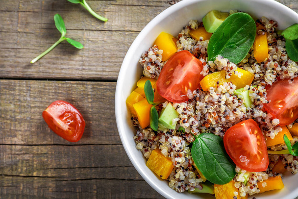 Quinoa salad with tomatoes, batata and spinach on wooden background. Vegan food concept. Top view. - Photo, Image