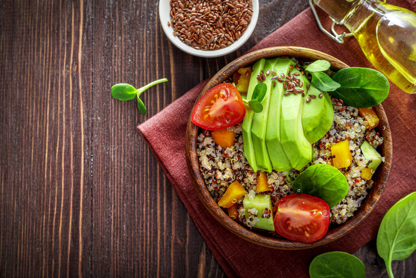 Comedor vegetariano saludable con quinua, aguacate, tomates, espinacas y semillas sobre fondo de madera. Vista superior. - Foto, Imagen
