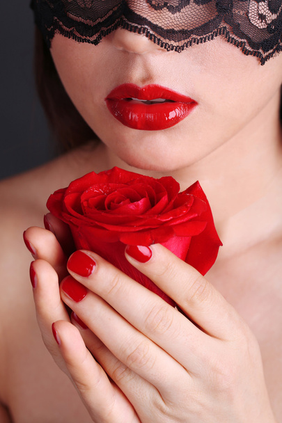 Girl with red lips, nails and openwork black eye on dark background - Foto, Imagen