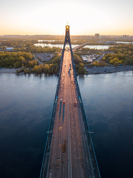 Puente norte en Kiev. Rayos de sol saliendo a lo largo del puente. Amanecer a través del pilón. Vista aérea del dron. - Foto, imagen