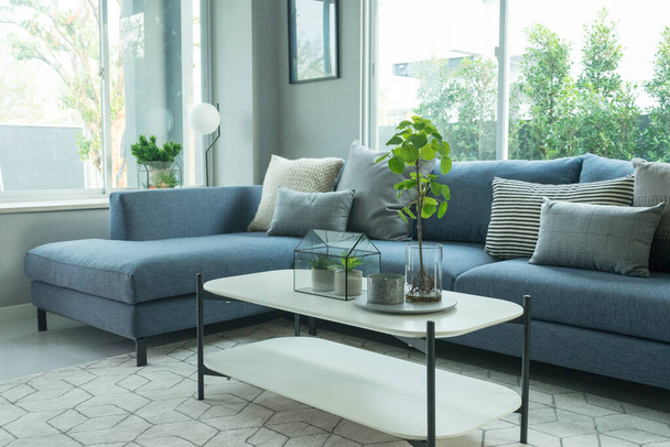 Salón moderno y elegante, sofá azul y almohada gris con mesa de centro, alfombra y lámpara de pie. - Foto, Imagen