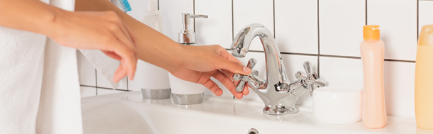 обрезанный вид женских молодых рук касающихся крана перед мытьем в ванной комнате, баннер - Фото, изображение