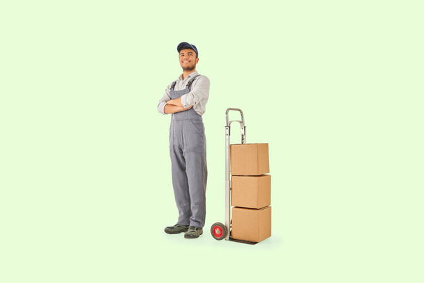 Self confident delivery man with hand truck trolley brown cardboard box style. Colorful background. - Photo, Image