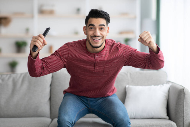 Onnellinen arabi kaveri katsomassa urheilua televisiosta kotona - Valokuva, kuva