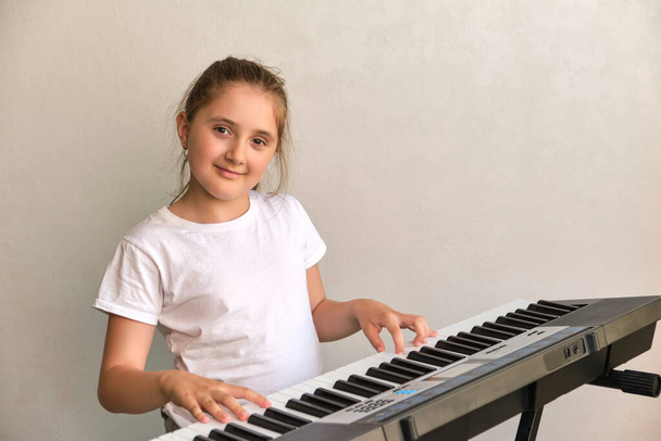 Πορτρέτο του χαριτωμένο χαρούμενο χαμογελαστό κορίτσι που παίζει ηλεκτρικό πιάνο - Φωτογραφία, εικόνα