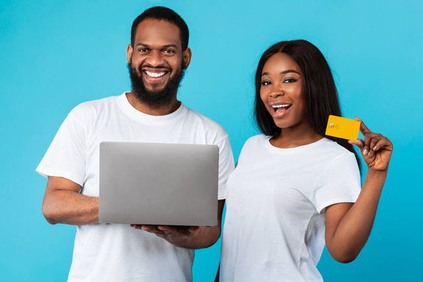 Famille noire utilisant un ordinateur et une carte de crédit au studio bleu - Photo, image