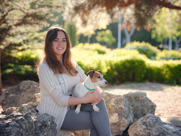 Nuori nainen söpö Jack Russell Terrier ulkona. Ihana lemmikki. Miellyttävä kevät-ilta onnellisella kävelyllä - Valokuva, kuva