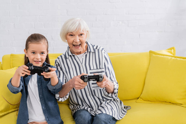 KYIV, UKRAINE - JANUARY 11, 2021: Grandmother and kid playing video game during competition  - Фото, зображення
