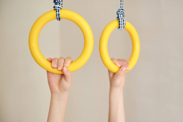 Children's hands holding gymnastic rings. Arm muscle training. Childhood, Physical, Hand Coordination, Sensory, Motor Skills development concept. Text space - Photo, Image