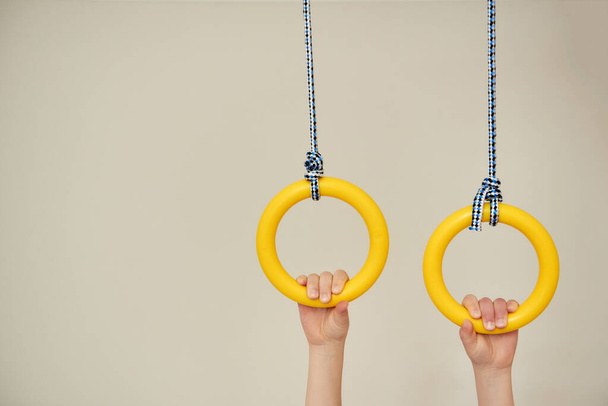 Image with space for text children's hands holding gymnastic rings. Arm muscle training. Childhood, Physical, Hand Coordination, Sensory, Motor Skills development concept - Photo, Image