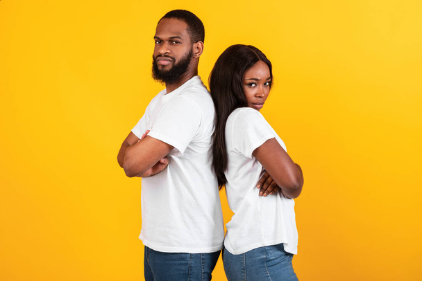 Afro pareja de pie espalda con espalda, amarillo anaranjado estudio pared - Foto, imagen