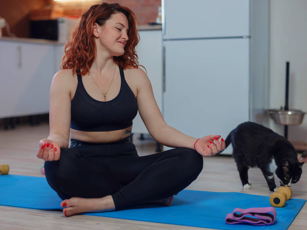 Online Training. Fit Young Woman Excersising At Home with her cat, Watching to smartphone. Self-isolation is beneficial, entertainment and education on the Internet. Healthy lifestyle concept. - Photo, Image