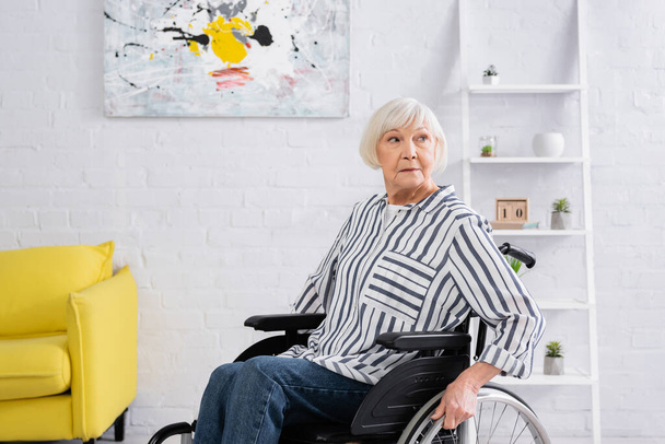 Mujer mayor sentada en silla de ruedas en el salón  - Foto, Imagen