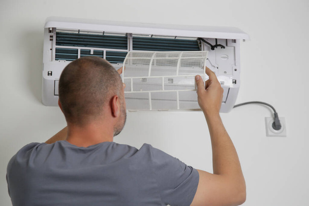 Homme mettant un nouveau filtre à air propre sur le climatiseur. - Photo, image