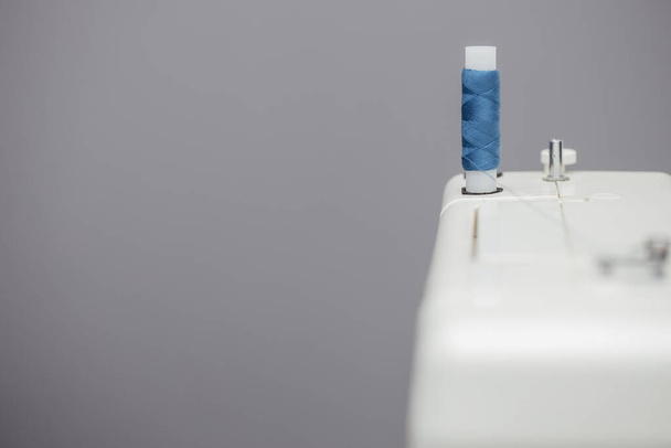 Котушка з синіми нитками, встановленими на швейній машинці
 - Фото, зображення