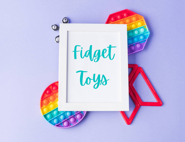 Conjunto de juguetes de fidget coloridos para el estrés anti en púrpura con texto en marco blanco - Foto, imagen
